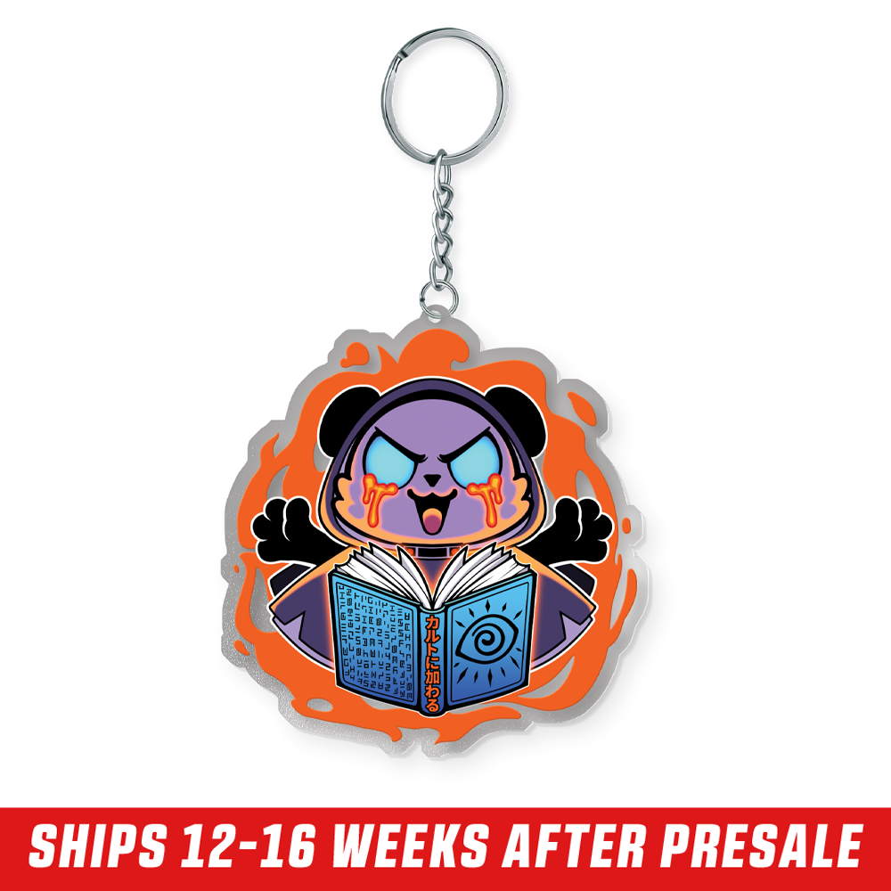 Purple cartoon bear with glowing blue eyes and orange tears holding a blue book surrounded by an orange flame design keychain